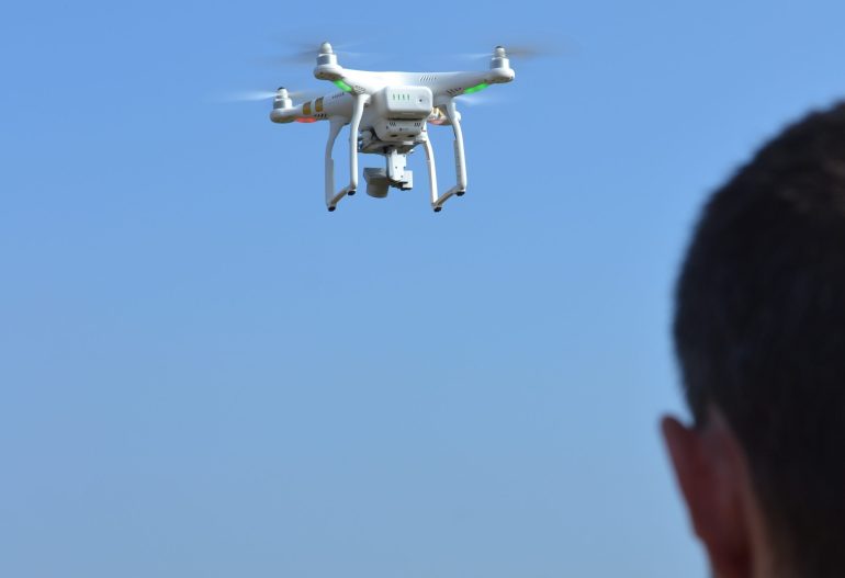 Silhouette of a drone operator in the foreground flying a UAV