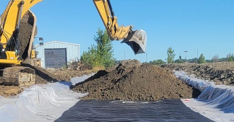 Biopiles being loaded on plastic sheet by an excavator