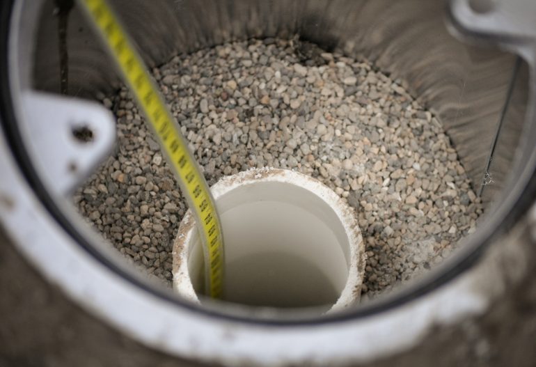 A water level measuring tape entering into a groundwater monitoring well Phase Two ESA
