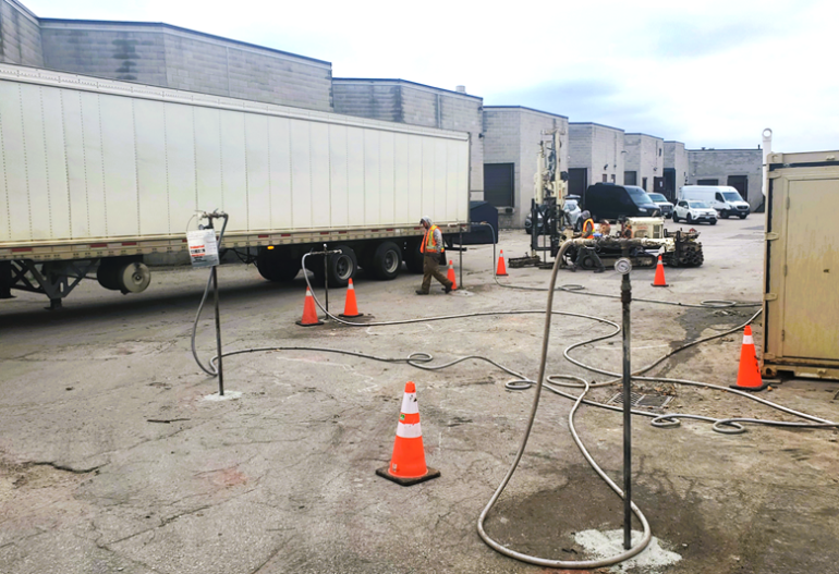 Four injection points actively injecting and a fifth being installed in the background while a large semi-trailer delivery truck drives by the work area.