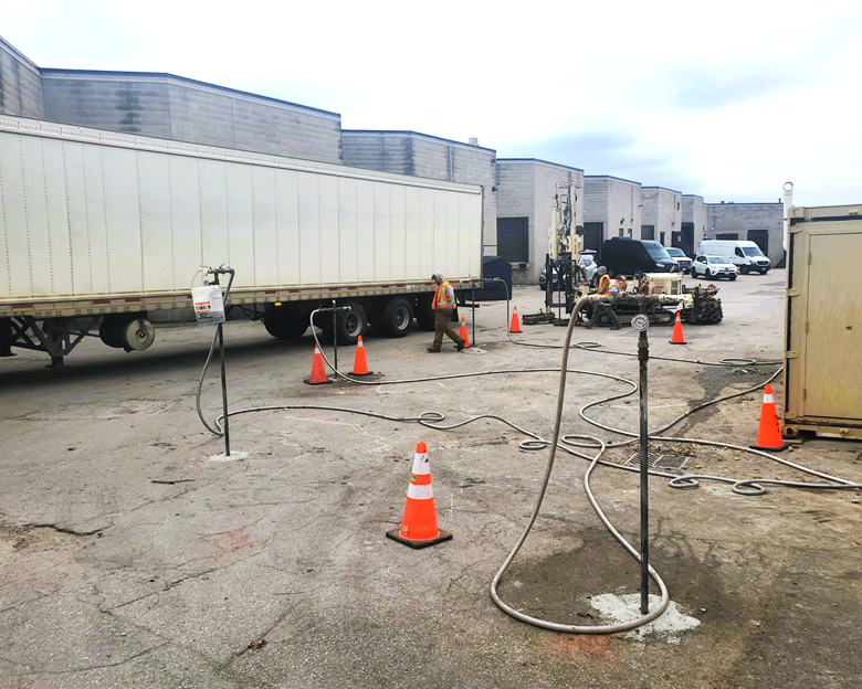 Four injection points actively injecting and a fifth being installed in the background while a large semi-trailer delivery truck drives by the work area.